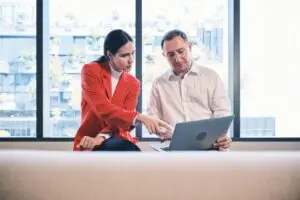 Zwei Kollegen besprechen Unterlagen gemeinsam am Laptop