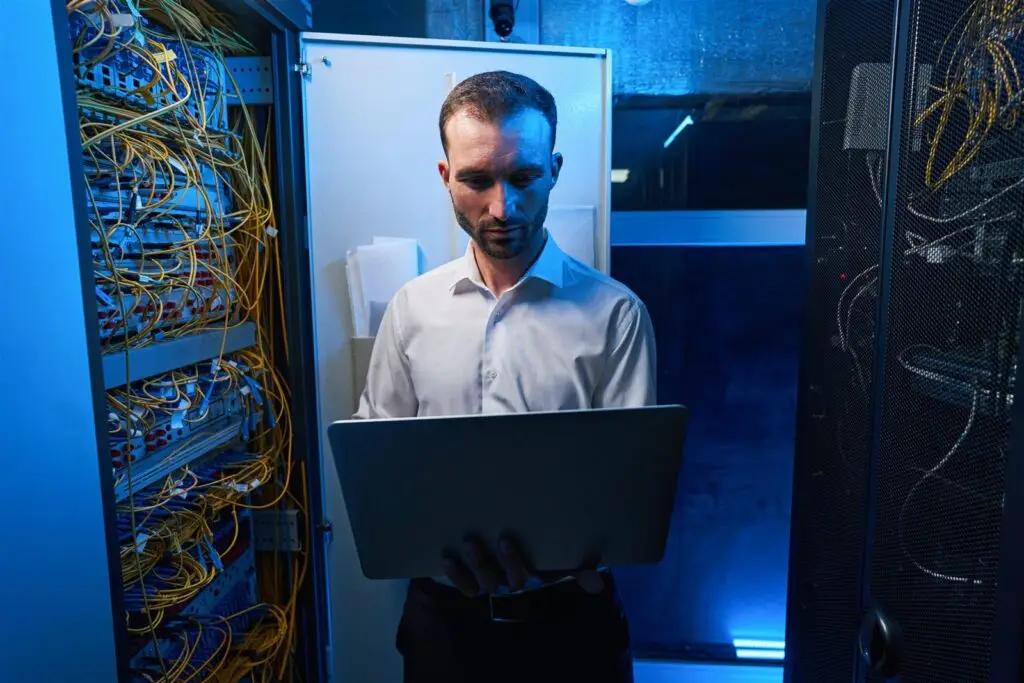 IT-Fachkraft prüft mit dem Laptop einen offenen Serverschrank