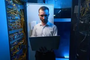 IT-Fachkraft prüft mit dem Laptop einen offenen Serverschrank